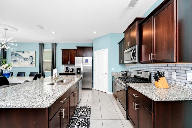 kitchen featuring light tile patterned floors, stainless steel appliances, visible vents, a sink, and an island with sink