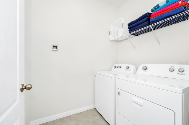 washroom with washing machine and dryer, laundry area, baseboards, and light tile patterned floors