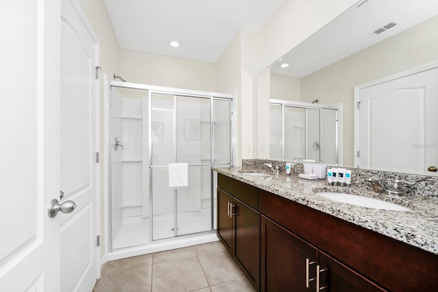 bathroom with a shower stall, a sink, visible vents, and tile patterned floors