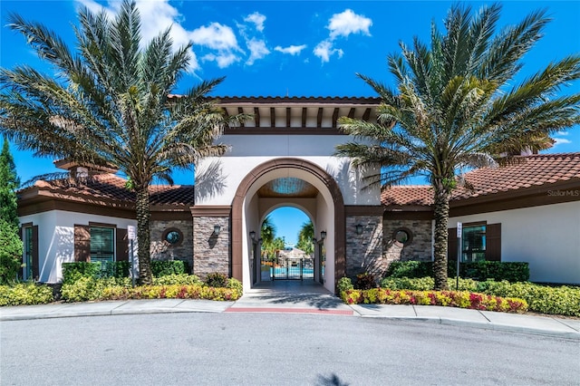 property entrance featuring stone siding, a tiled roof, a gate, and stucco siding