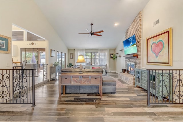 living area featuring a brick fireplace, plenty of natural light, and wood finished floors