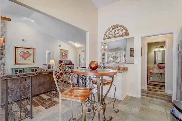 dining space featuring high vaulted ceiling, visible vents, baseboards, and an inviting chandelier