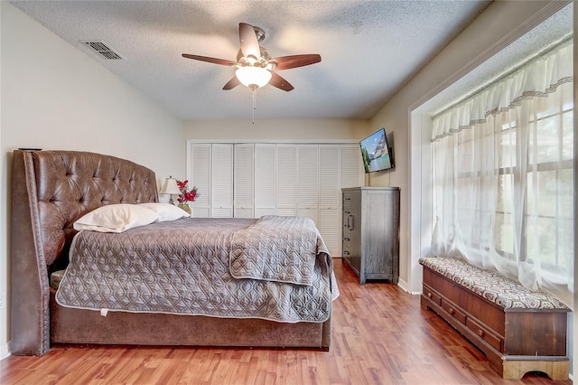 bedroom featuring visible vents, ceiling fan, a textured ceiling, and wood finished floors