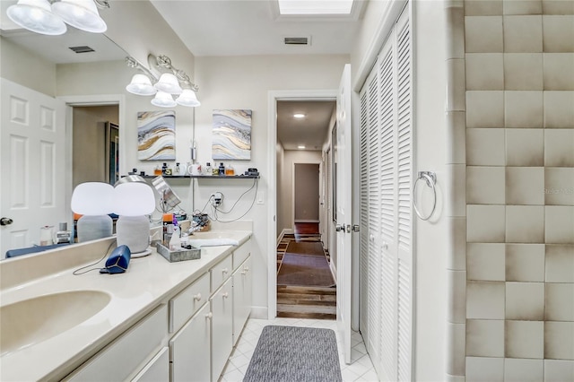 bathroom featuring tile patterned flooring, a closet, a sink, and double vanity