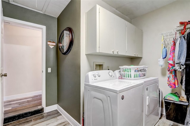 clothes washing area featuring baseboards, wood finished floors, cabinet space, and washer and dryer