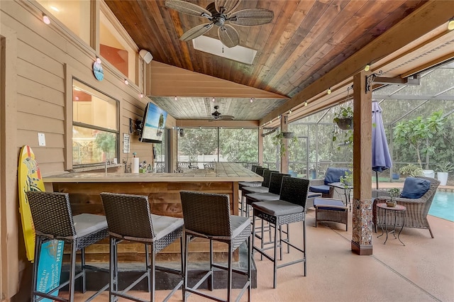 exterior space featuring glass enclosure, ceiling fan, and a bar