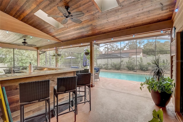 sunroom / solarium with plenty of natural light, vaulted ceiling, wooden ceiling, and a ceiling fan