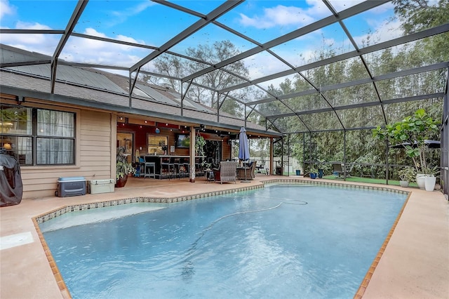 pool with glass enclosure, a patio, and a bar