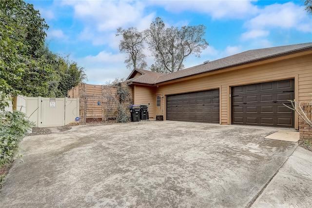 view of property exterior with concrete driveway and fence