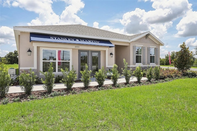 view of front of house with stone siding, a shingled roof, a front lawn, and stucco siding