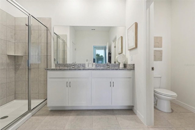 bathroom with toilet, a shower stall, vanity, baseboards, and tile patterned floors