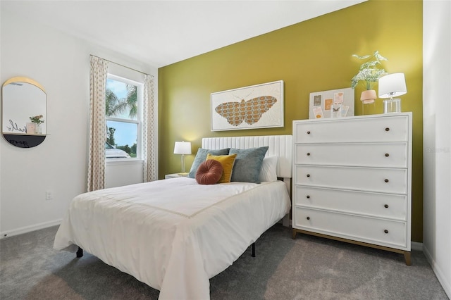 bedroom with dark carpet and baseboards