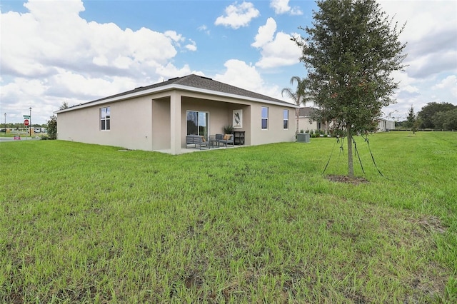 rear view of property with stucco siding, central AC unit, a patio, and a yard