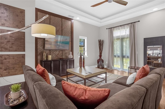 living room featuring recessed lighting, a raised ceiling, visible vents, light wood-style flooring, and a ceiling fan