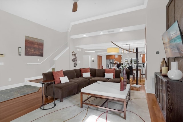 living area with light wood-style floors, baseboards, visible vents, and stairway