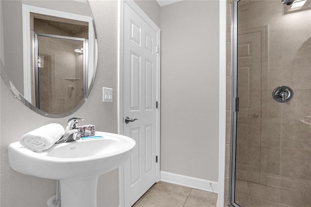 bathroom with a sink, a shower stall, baseboards, and tile patterned floors