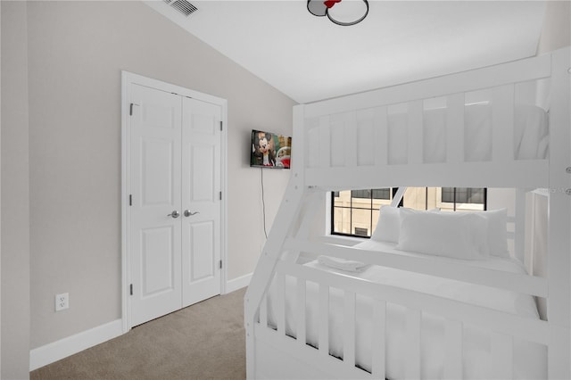 bedroom featuring lofted ceiling, a closet, light colored carpet, and baseboards