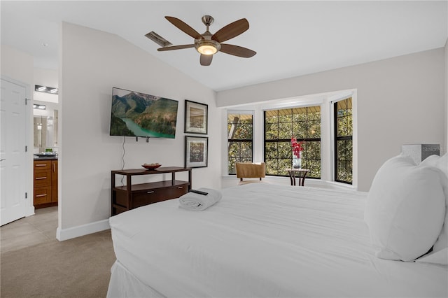 bedroom featuring visible vents, light carpet, vaulted ceiling, ensuite bath, and baseboards