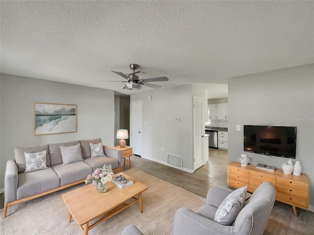 living area with ceiling fan, a textured ceiling, wood finished floors, and visible vents