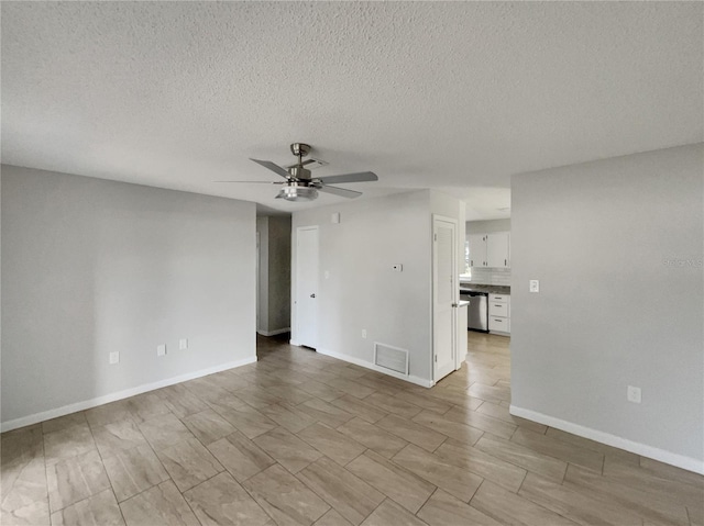 empty room with baseboards, a textured ceiling, visible vents, and a ceiling fan