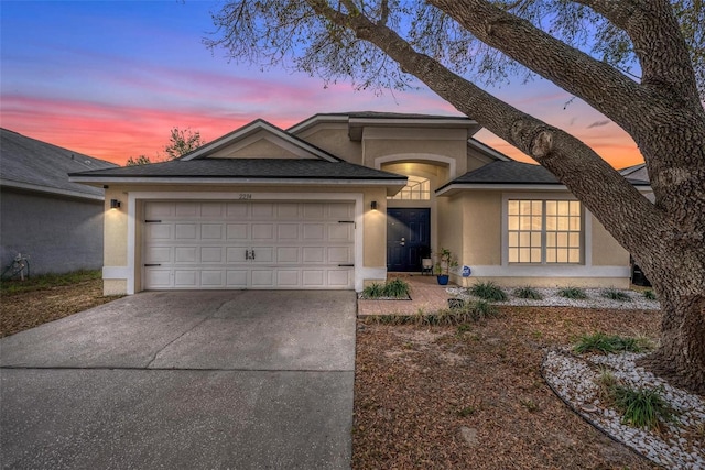 view of front of property with a garage, concrete driveway, and stucco siding