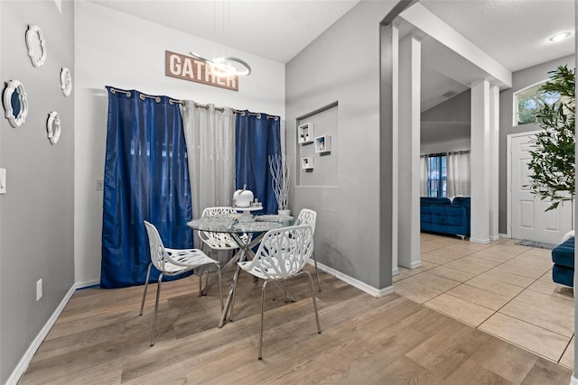 dining space featuring vaulted ceiling, baseboards, and wood finished floors