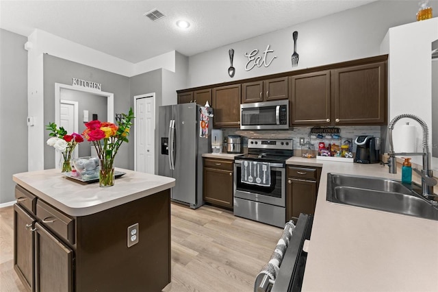 kitchen featuring light wood-type flooring, appliances with stainless steel finishes, light countertops, and a sink