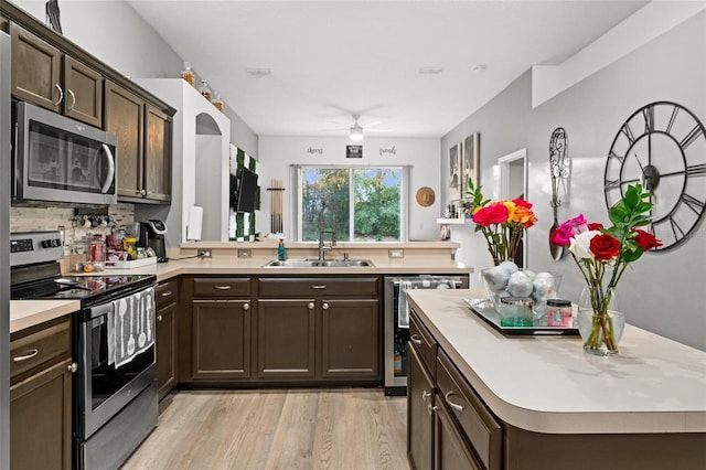 kitchen with light countertops, appliances with stainless steel finishes, a peninsula, and a sink