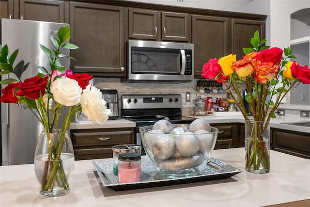 kitchen with decorative backsplash, appliances with stainless steel finishes, light countertops, and dark brown cabinets