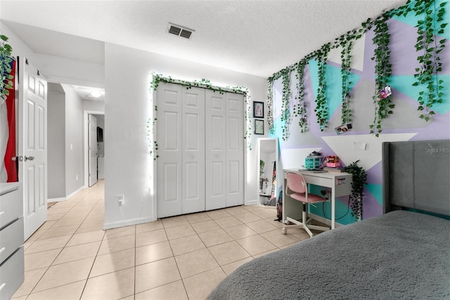 foyer entrance with a textured ceiling, light tile patterned flooring, visible vents, and baseboards