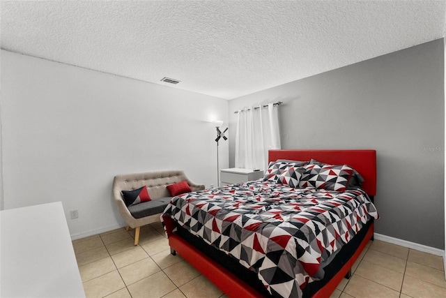 bedroom with light tile patterned floors, baseboards, visible vents, and a textured ceiling