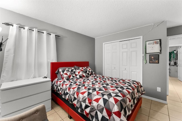 bedroom featuring light tile patterned floors, a textured ceiling, and a closet