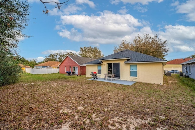 rear view of property featuring central AC, fence, a yard, stucco siding, and a patio area