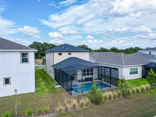 back of property featuring a yard, glass enclosure, an outdoor pool, and stucco siding