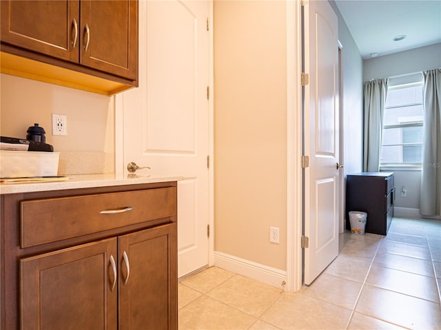 interior space featuring brown cabinets, light tile patterned floors, baseboards, and light countertops