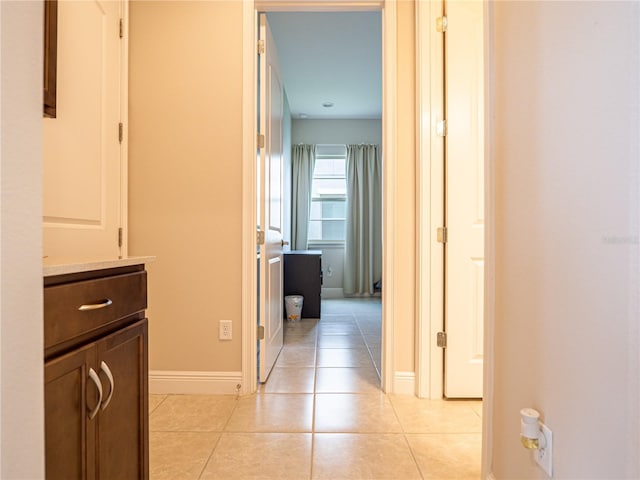 hall with light tile patterned flooring and baseboards