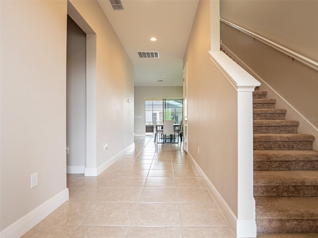 hallway featuring tile patterned flooring, visible vents, and baseboards