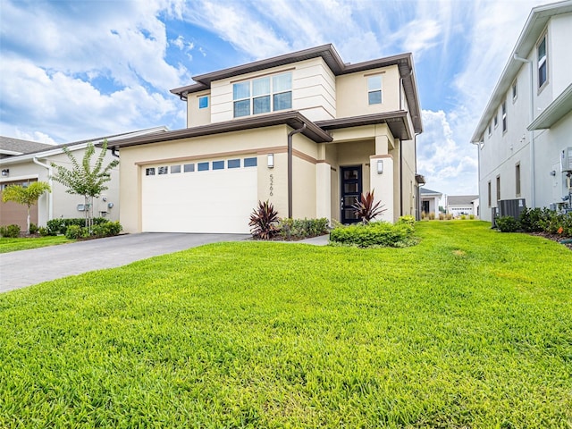 prairie-style house with an attached garage, a front lawn, aphalt driveway, and stucco siding