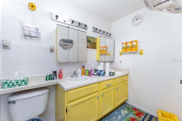 bathroom with baseboards, a sink, toilet, and double vanity