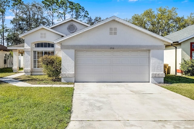 view of front of property featuring a front yard, driveway, an attached garage, and stucco siding