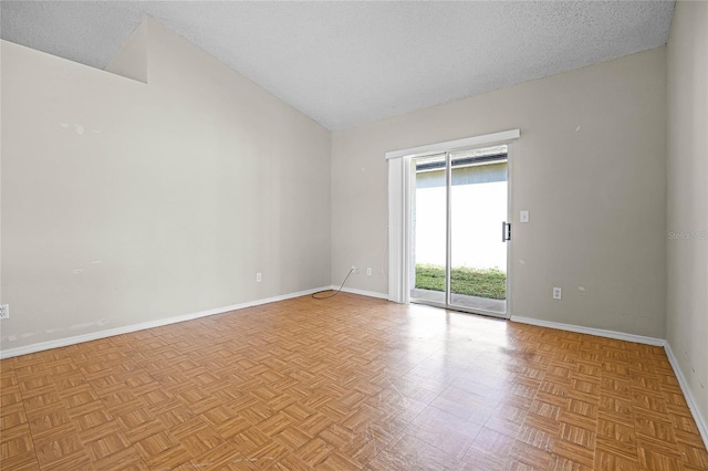 spare room with vaulted ceiling, a textured ceiling, and baseboards