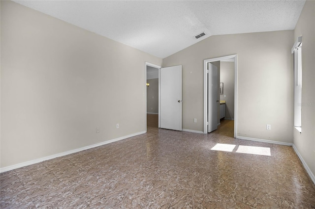 unfurnished room with lofted ceiling, baseboards, visible vents, and a textured ceiling