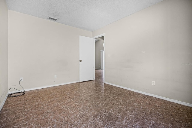 empty room with a textured ceiling, visible vents, and baseboards