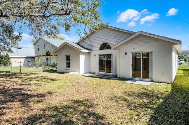 rear view of house with fence and a lawn