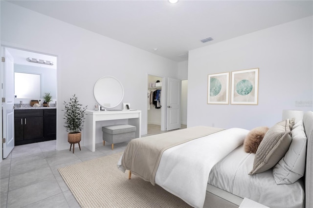 bedroom with visible vents, ensuite bathroom, a walk in closet, and light tile patterned flooring