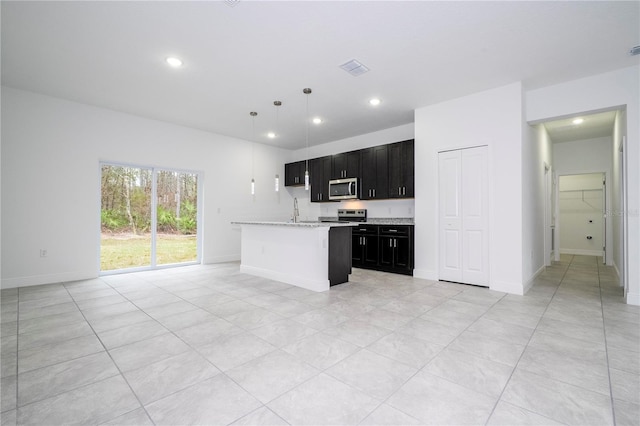 kitchen featuring a sink, open floor plan, recessed lighting, stainless steel appliances, and dark cabinets