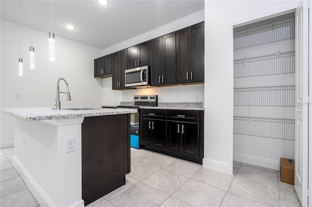 kitchen with hanging light fixtures, light tile patterned floors, appliances with stainless steel finishes, and a sink