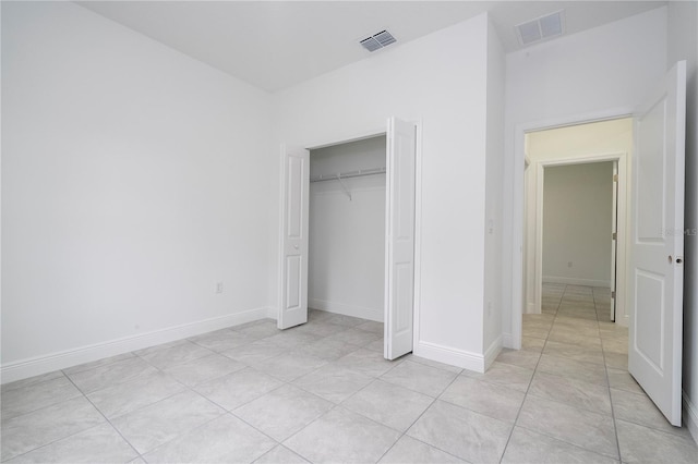 unfurnished bedroom featuring light tile patterned flooring, baseboards, visible vents, and a closet