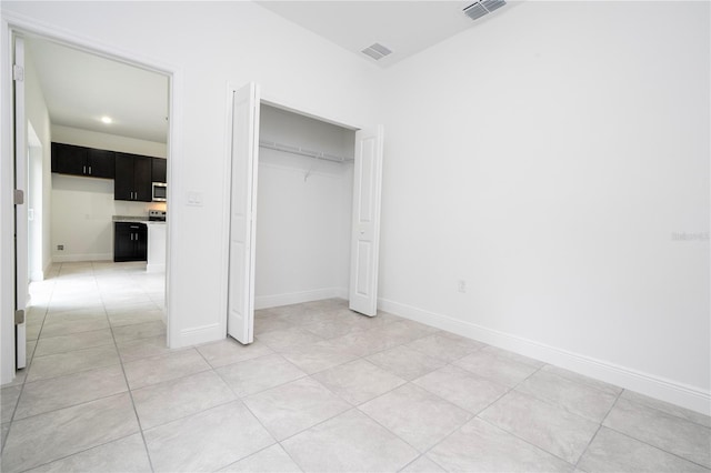 unfurnished bedroom featuring visible vents, baseboards, a closet, and light tile patterned flooring