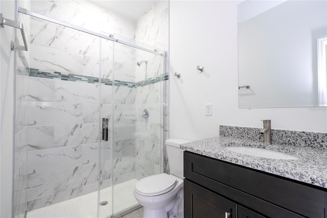 bathroom featuring a shower stall, toilet, and vanity